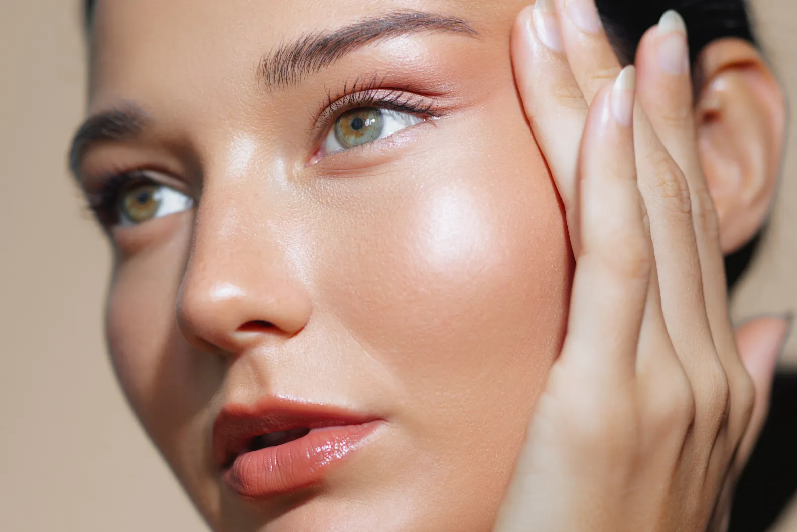 Schönheit-Heilung-Weilheim Frau mit strahlender Haut, die ihr Gesicht in Nahaufnahme streichelt zur Kollagen Behandlung der Heilpraxis Schönheilen in Weilheim bei Schongau